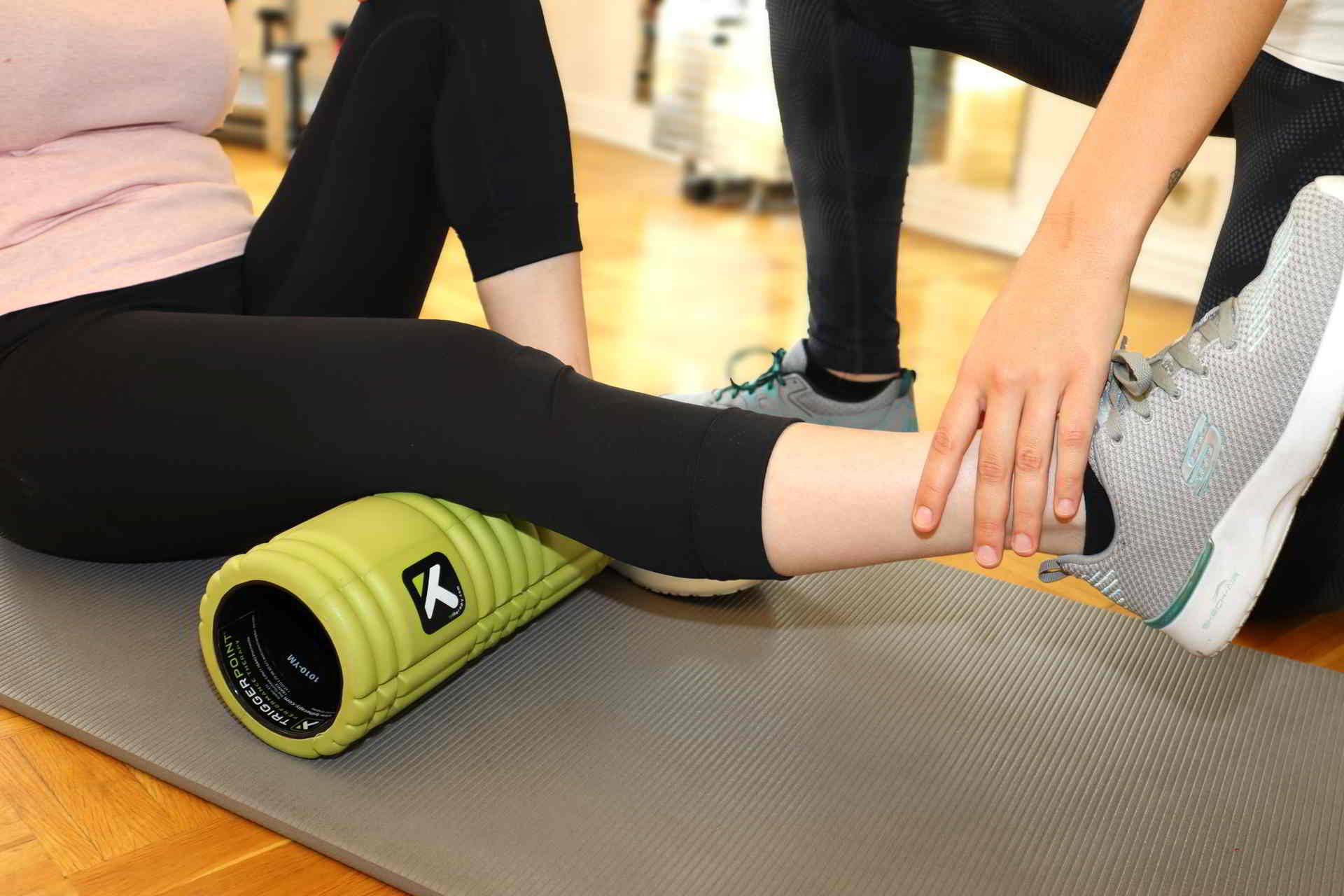 Patientin hat die Kniebeuge auf einer Faszienrolle