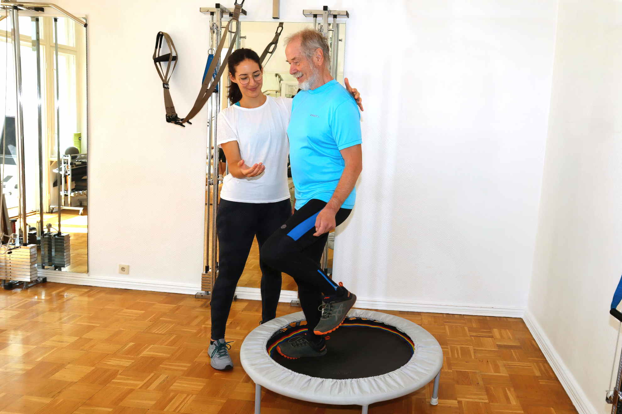 Trainerin hilft Patient auf dem Trampolin