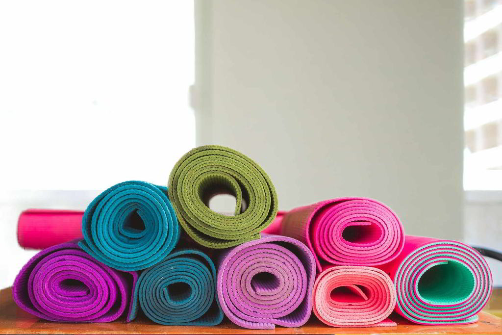 Verschiedenfarbige Trainingsmatten liegen zusammengerollt übereinander